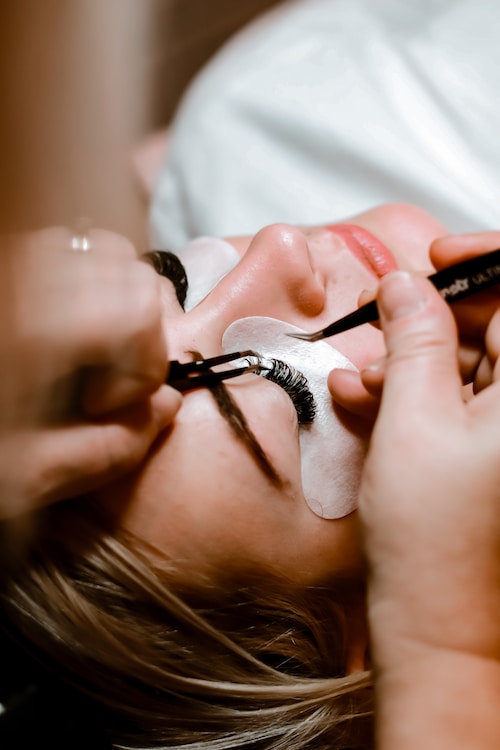 Lash extensions being placed using tweezers.